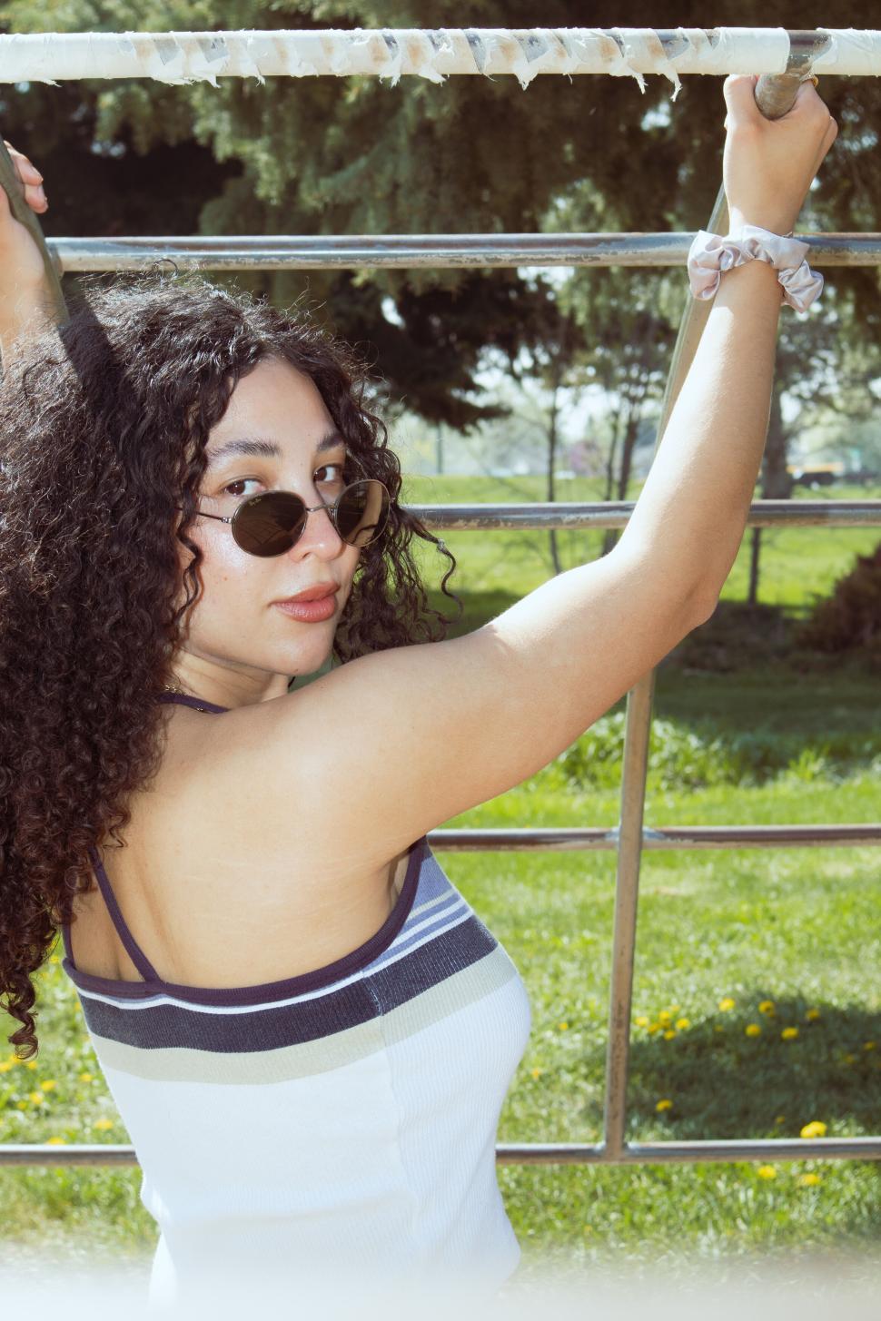 Free Image of Woman Exercising on Outdoor Pull-Up Bar by Lush Trees 