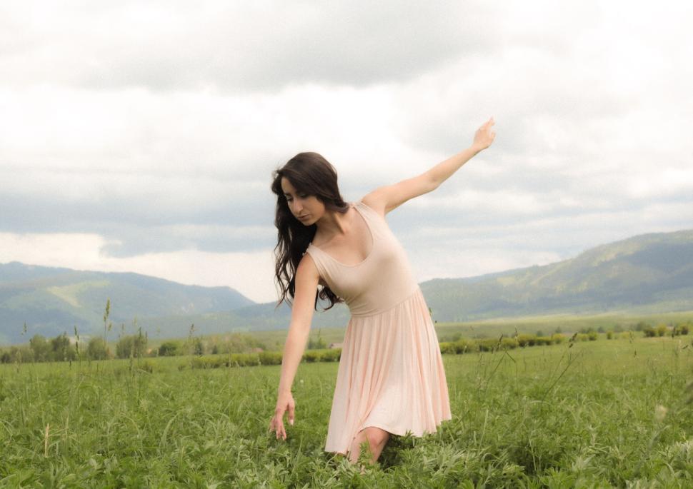 Free Image of Person in light dress leaning in grassy field outdoors 
