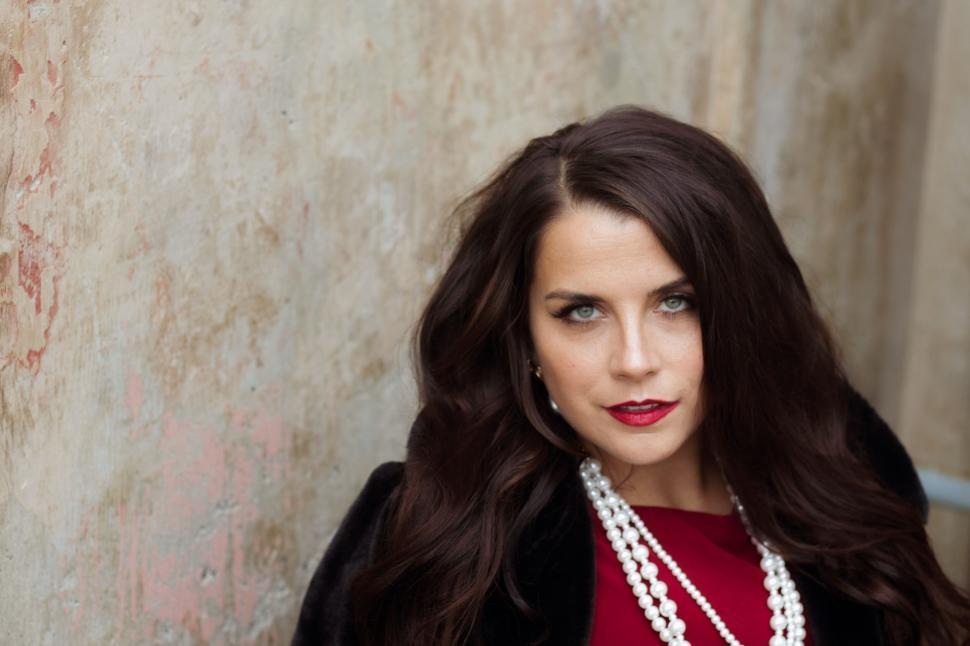 Free Image of Person against rustic wall adorned with layered jewelry 