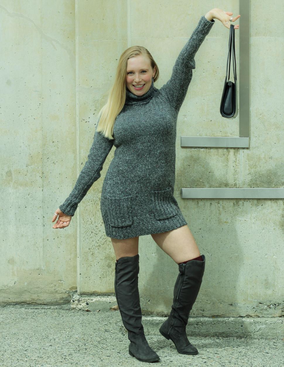 Free Image of Woman striking a pose in a sweater dress and high boots 