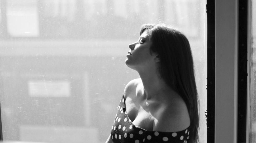 Free Image of Woman in polka dot dress gazing outside through window 