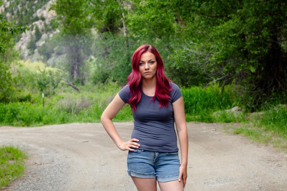 Free Image of Woman with red hair standing on a dirt path outdoors 