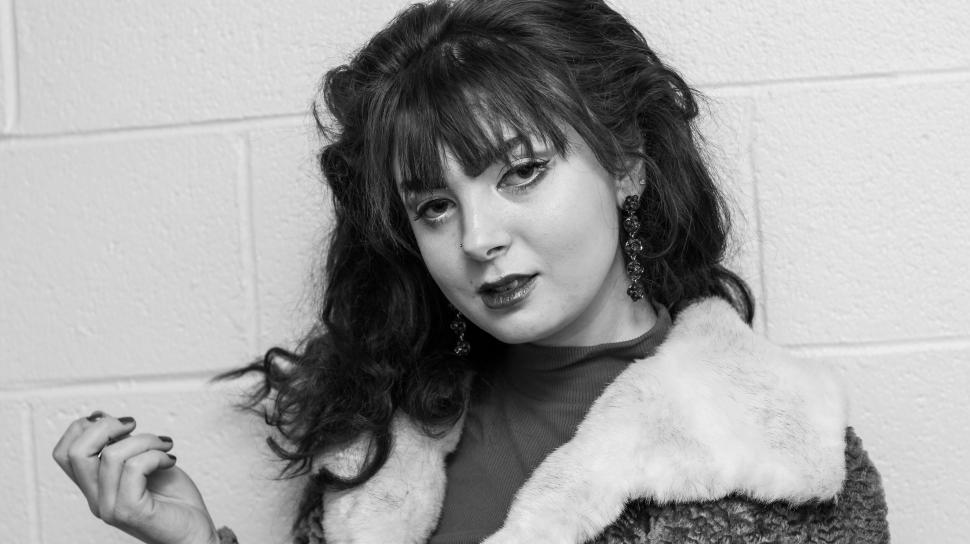 Free Image of Woman with wavy hair and fur coat against brick wall 