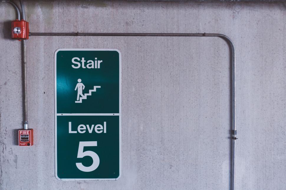 Free Image of Green stair level 5 sign on concrete wall with pipe 