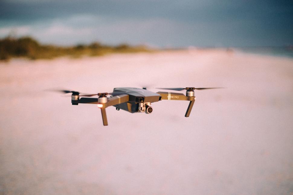 Free Image of Drone hovering over a sandy beach with blurred background. 