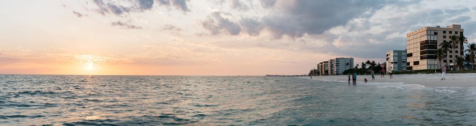 Free Image of Serene beachfront with sunset, modern buildings in view. 