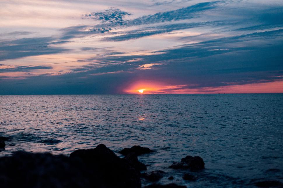 Free Image of Sunset over the ocean with dramatic sky and horizon view 