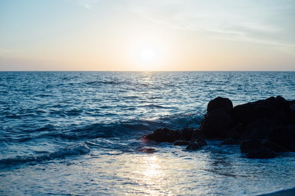 Free Image of Sunset over ocean with reflection on calm water surface. 