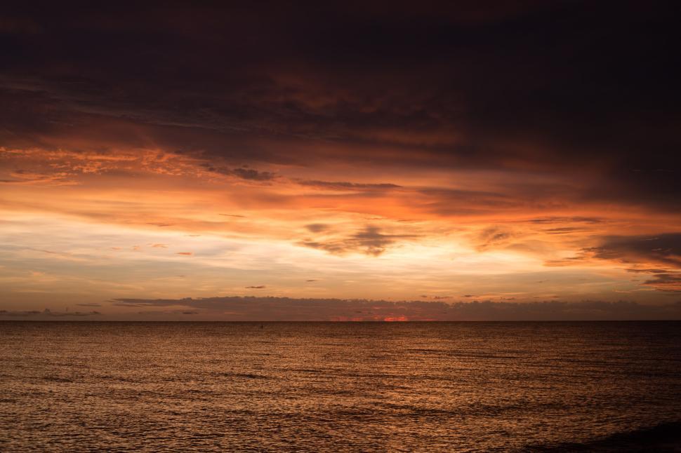 Free Image of Sunset over calm ocean, warm hues and tranquil ambiance 