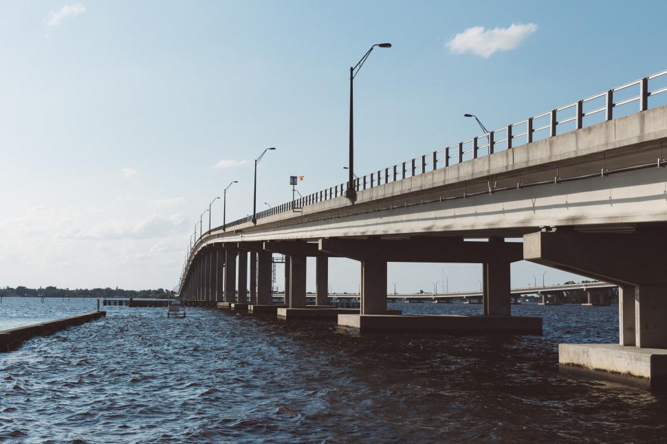 Free Image of Concrete bridge extending over a large body of water 