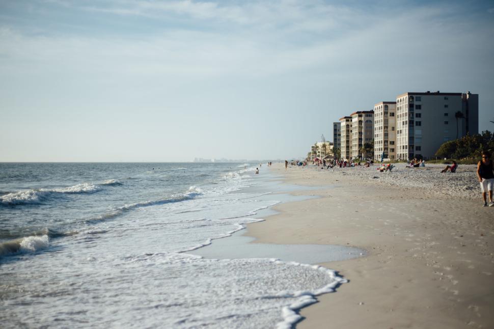 Free Image of A busy beach with shoreline and distant buildings visible. 
