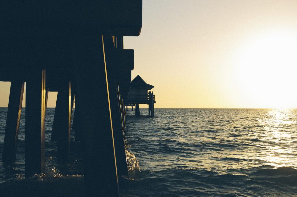 Free Image of Sunset view from a pier with a wooden hut in distance. 