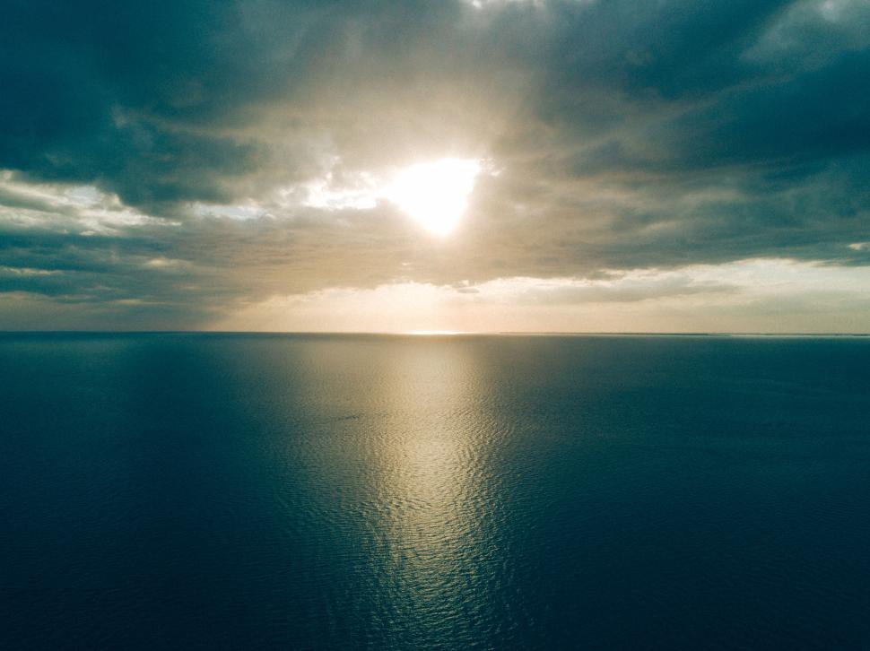 Free Image of Expansive ocean view with sun breaking through clouds. 