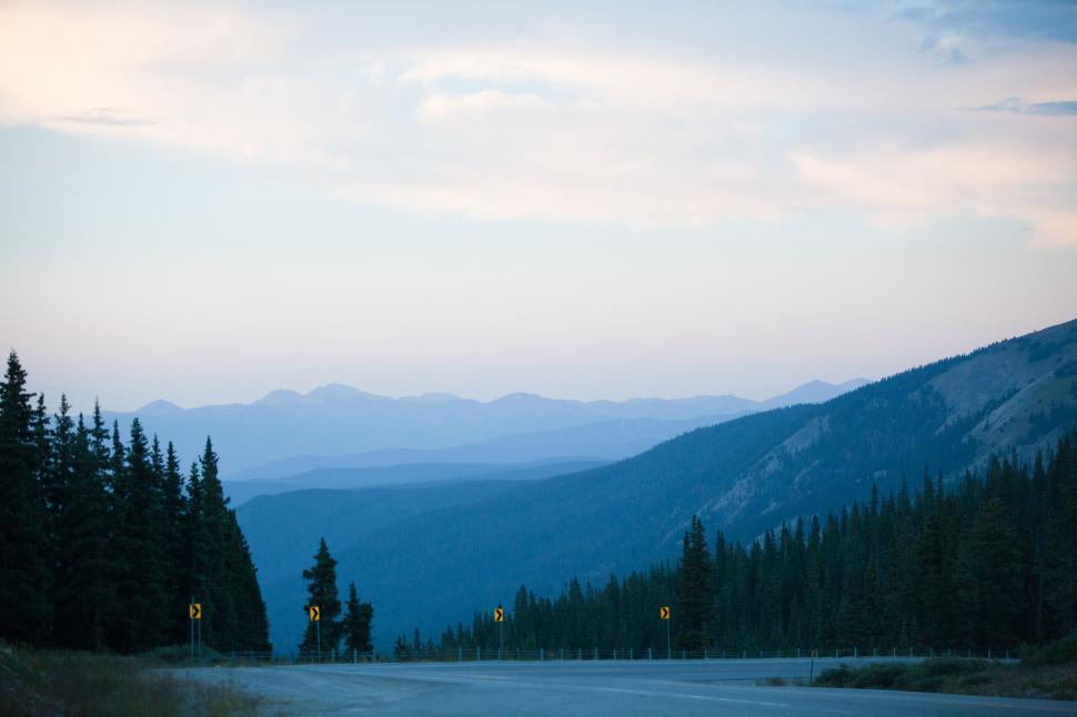 Free Image of Mountain road at dawn with pine trees and distant hills 