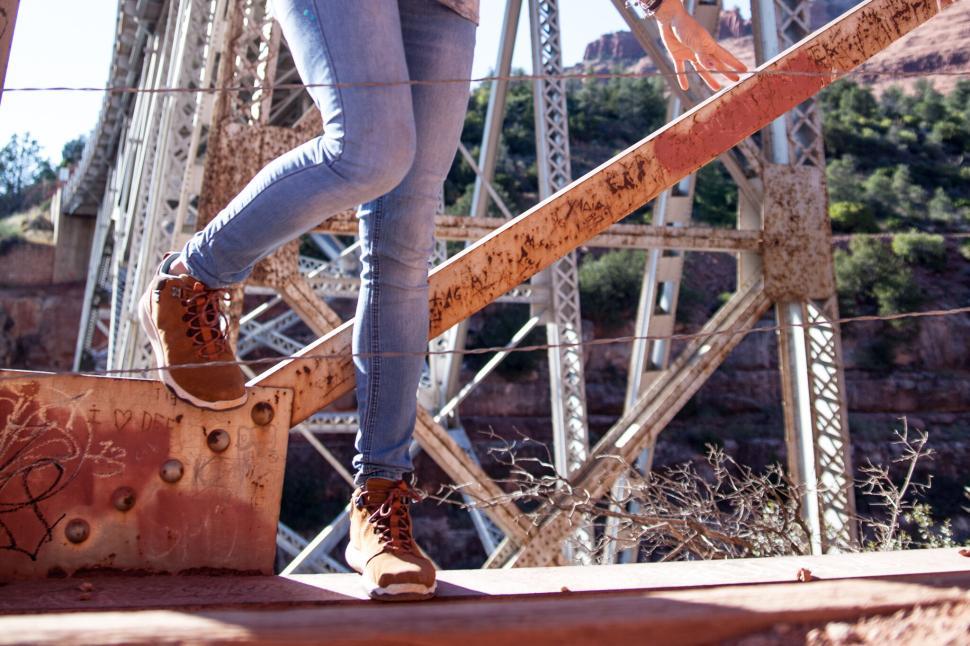 Free Image of Person crossing a bridge with metal structure background. 