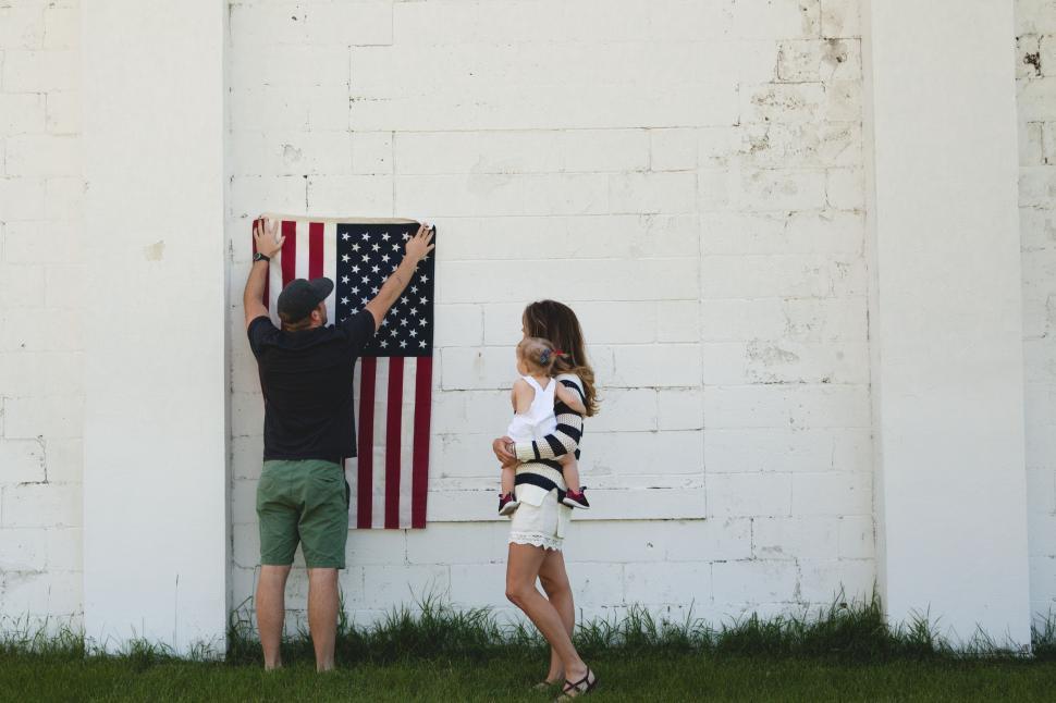 Free Image of Family hanging an American flag on a white wall 