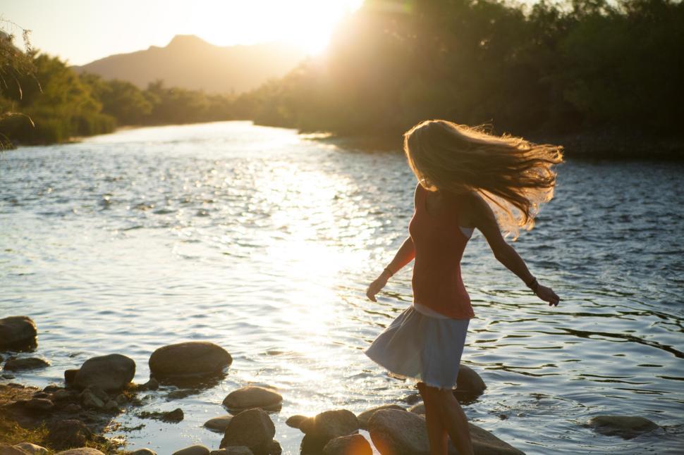 Free Image of Woman spinning by a river at sunrise in nature. 