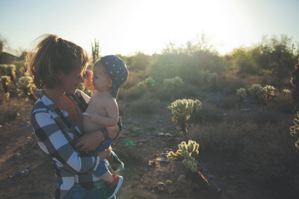 Free Image of Mother holding child in arid landscape with cacti. 