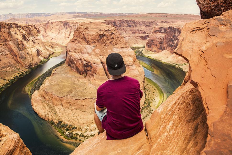 Free Image of Person sits above Horseshoe Bend s magnificent view. 