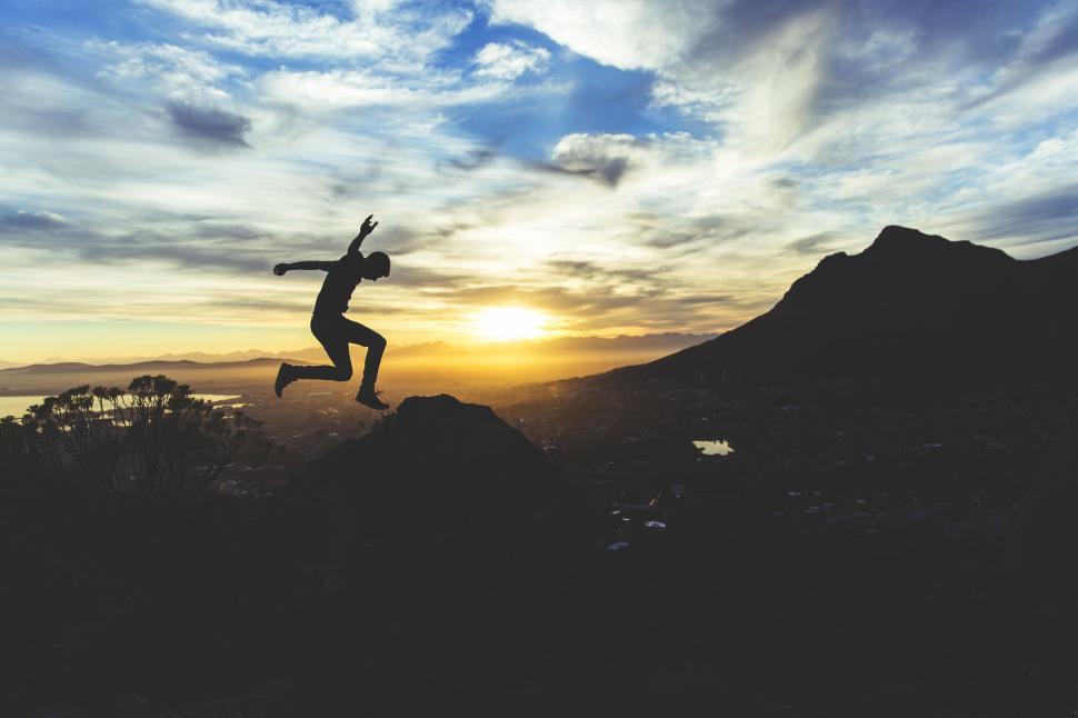Free Image of Silhouette of person jumping against a sunset sky 