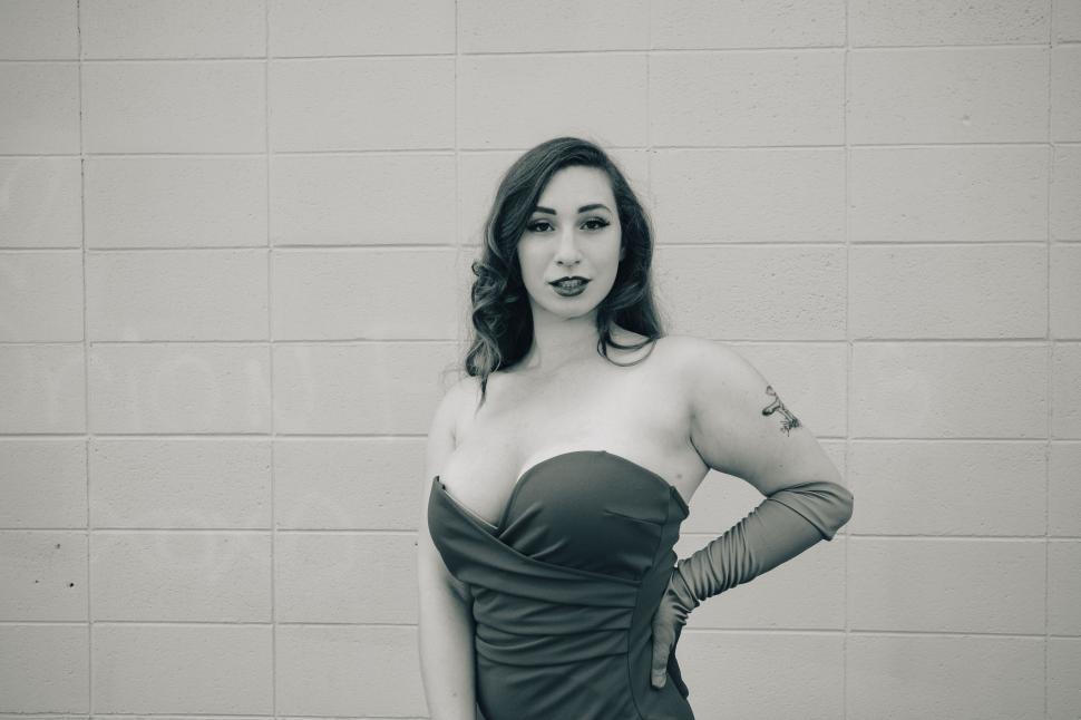 Free Image of Woman in formal dress posing against a tiled wall 