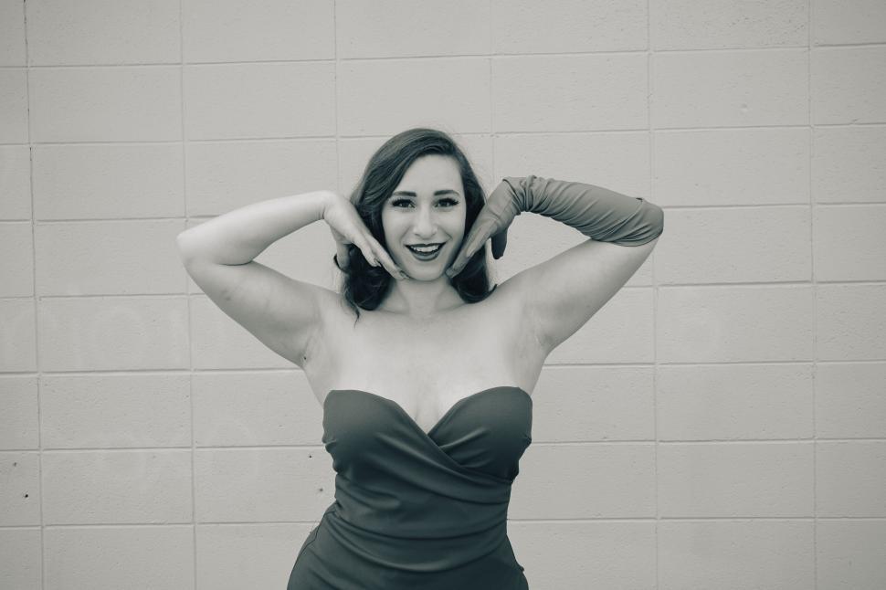 Free Image of Woman posing happily with hands on chin in a dress. 