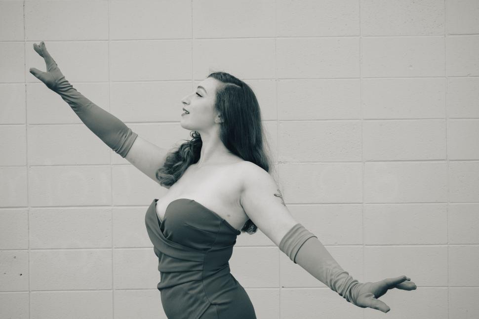 Free Image of Woman in elegant dress posing with arms extended in joy 