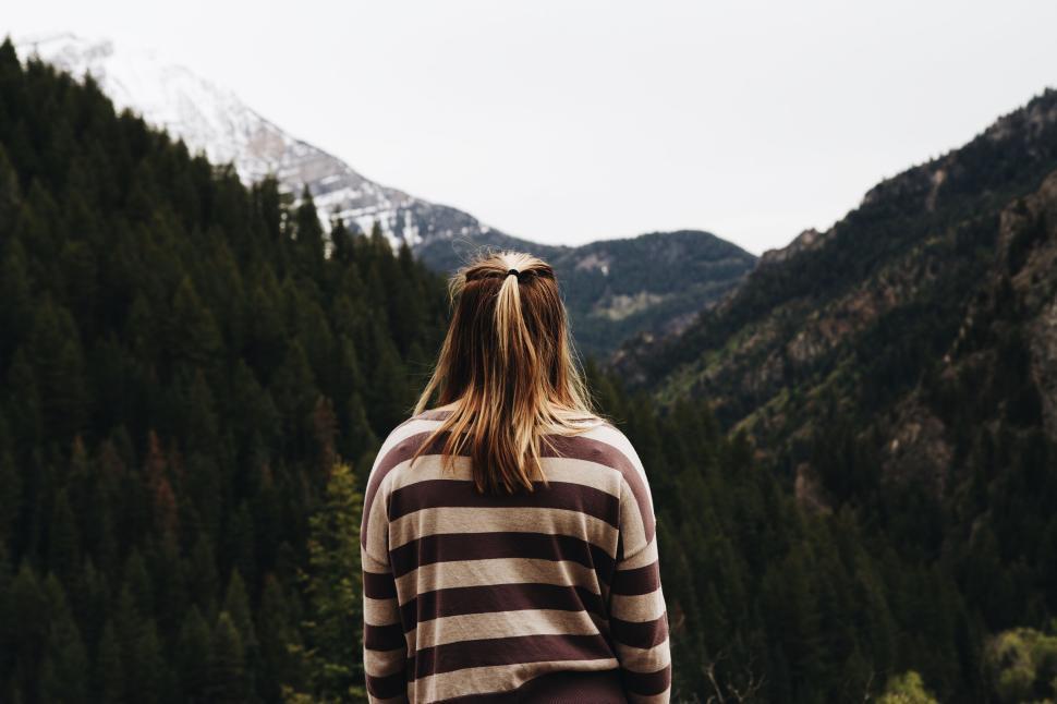Free Image of Back view of woman hiking in mountain forest with view 