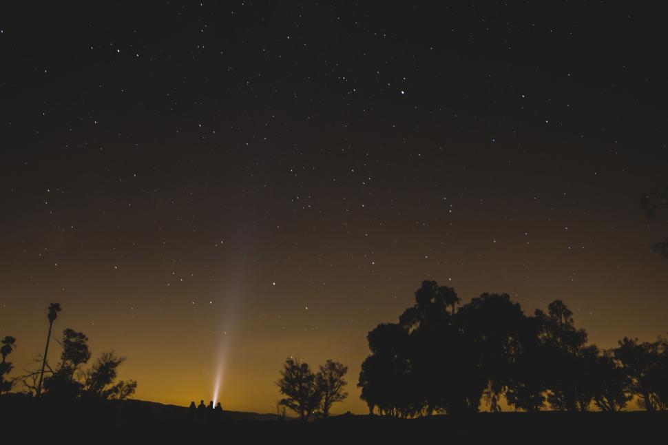 Free Image of Starry night sky with a beam of light on the horizon. 