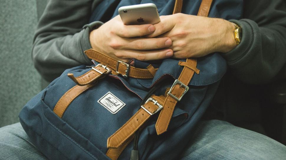 Free Image of Person using iPhone and wearing smartwatch seated casually 