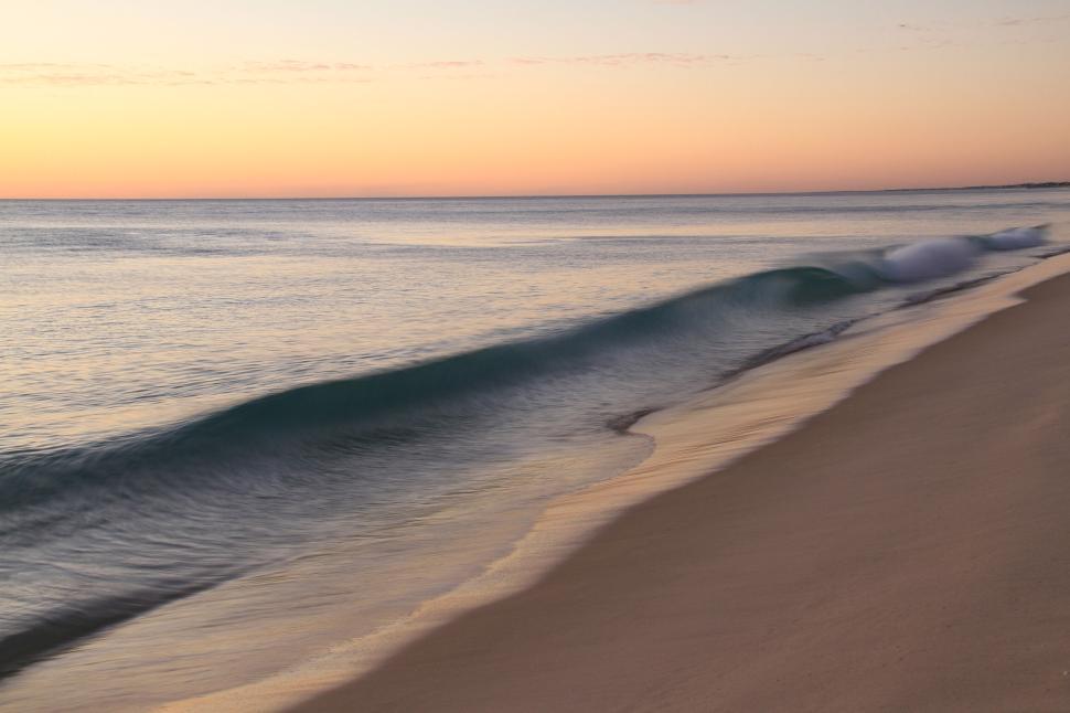 Free Image of Gentle waves washing ashore at a tranquil beach dawn 
