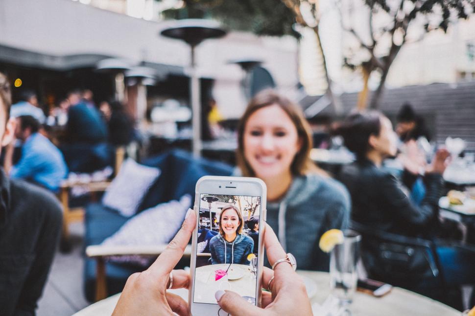 Free Image of People dining outdoors capturing moments using phone 