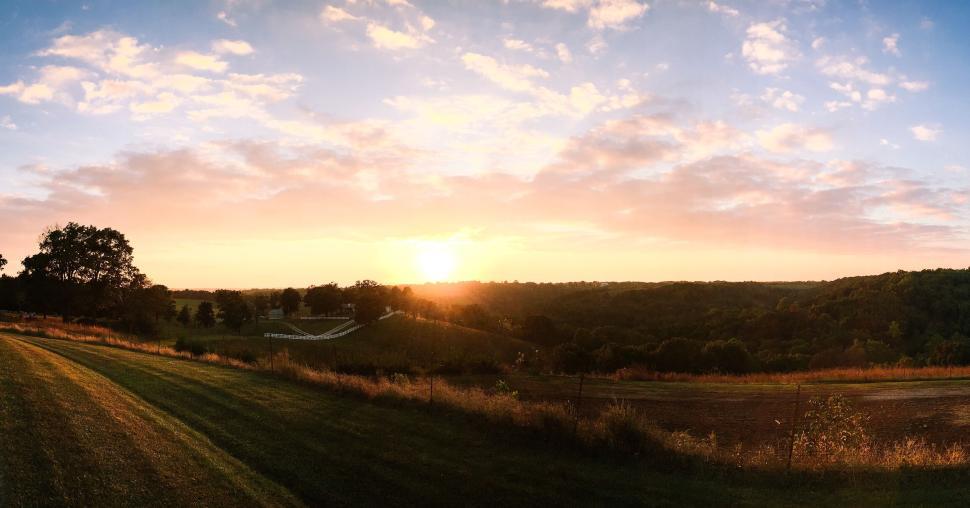 Free Image of Sunset over vast rolling hills with golden light. 