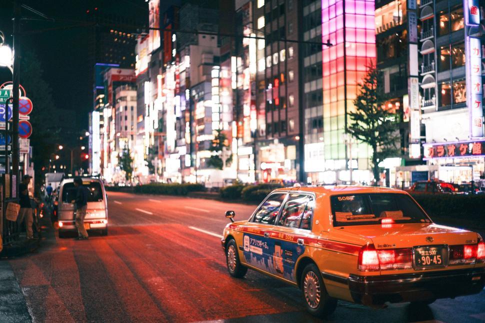 Free Image of Illuminated city street at night with taxis and buildings 