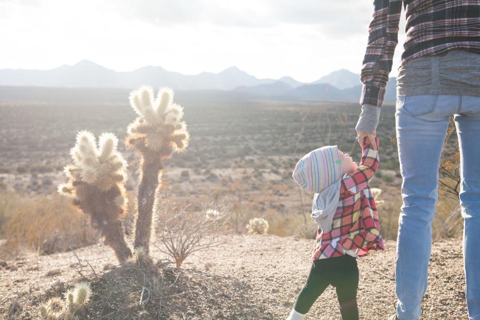 Free Image of Adult and child holding hands while in desert setting 