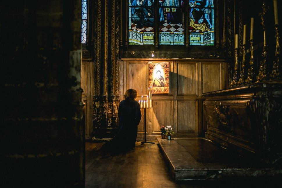 Free Image of Person praying in an ornate church candlelit interior. 