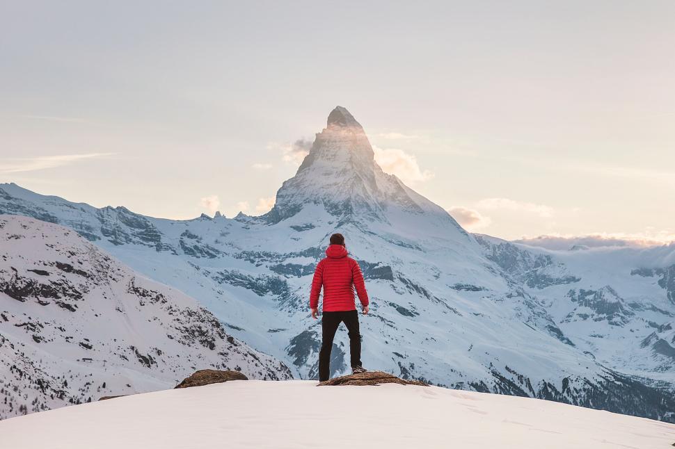 Free Image of Man in red jacket standing on snowy mountain peak 