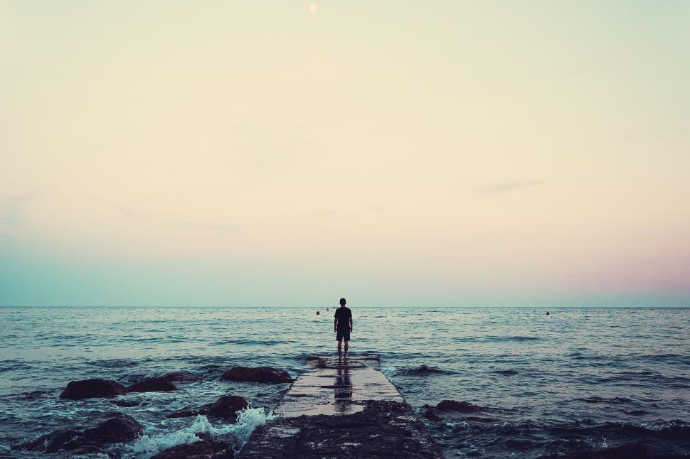 Free Image of Solitary figure on pier reaching towards the horizon. 