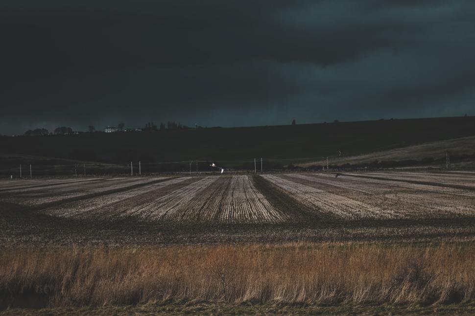 Free Image of Dark cloudy sky over a large agricultural field in rural setting 