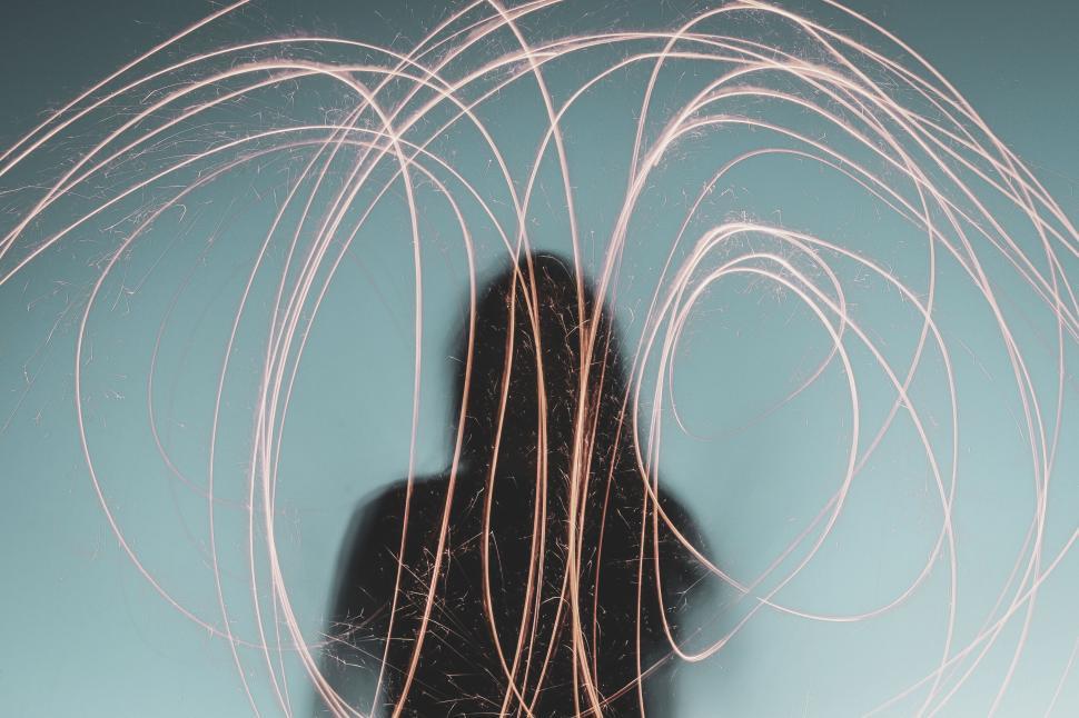 Free Image of Abstract long exposure of a person with light trails against blue sky 
