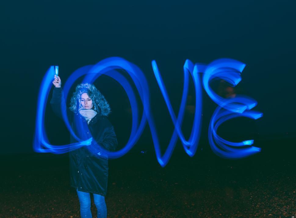 Free Image of Person with light arts draws the word  LOVE  with blue neon light. 