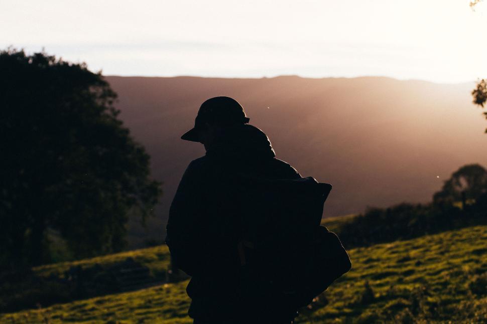 Free Image of Silhouette of a person standing in a field at sunrise or sunset. 