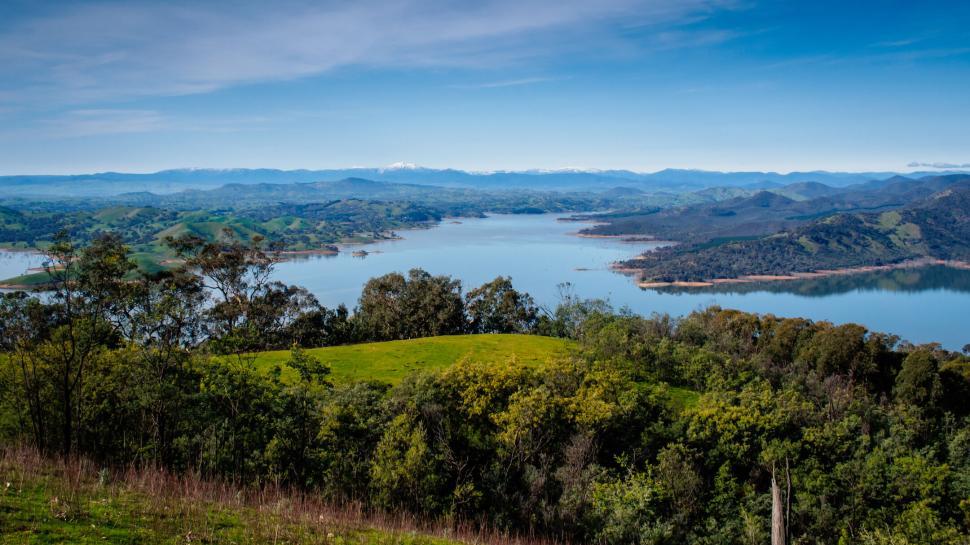 Free Image of Scenic view of a calm lake surrounded by lush green hillsides. 
