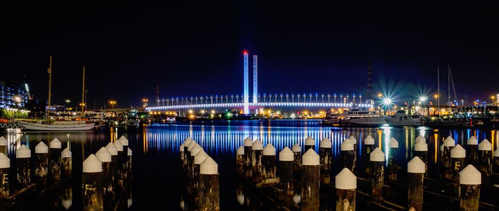 Free Image of Nighttime view of illuminated bridge over calm waterfront. 