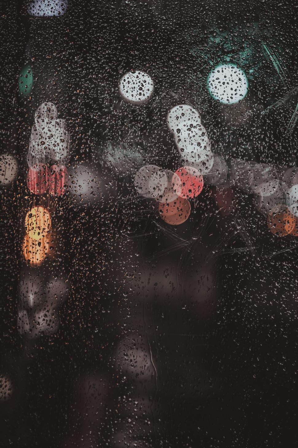Free Image of Raindrops on window glass creating abstract bokeh city lights view. 