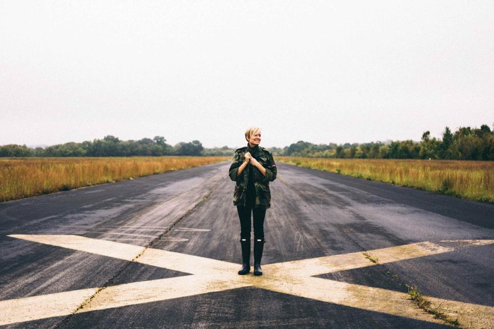 Free Image of Person standing on an empty highway, centered on X mark. 