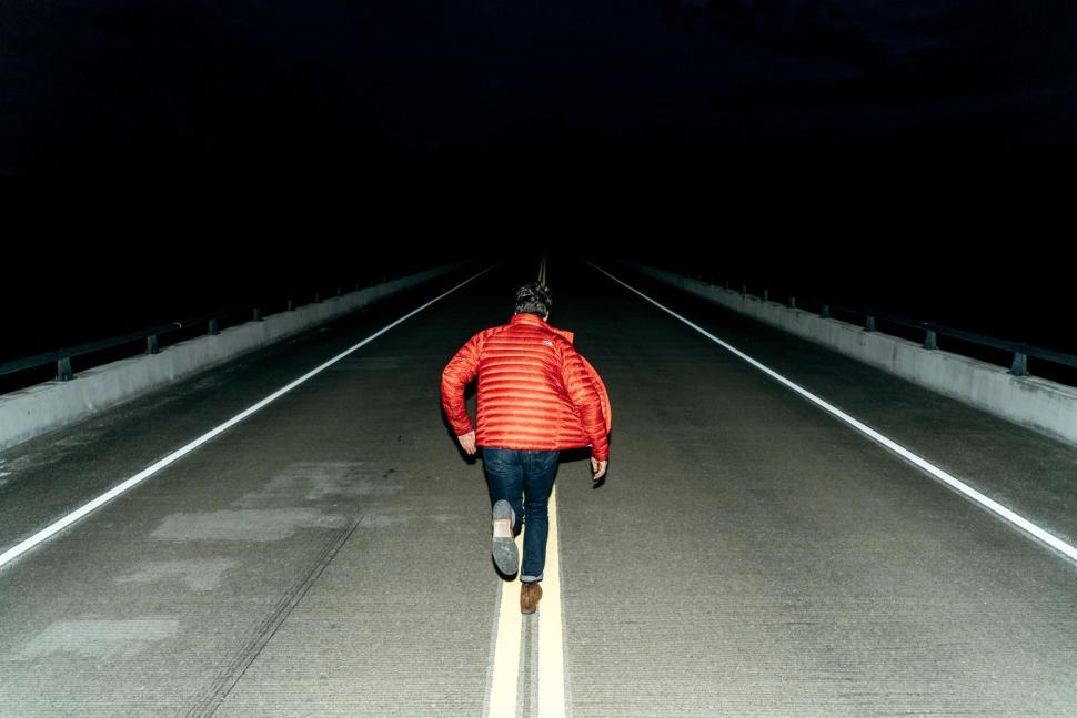 Free Image of Person in red jacket walking on an empty road at night. 