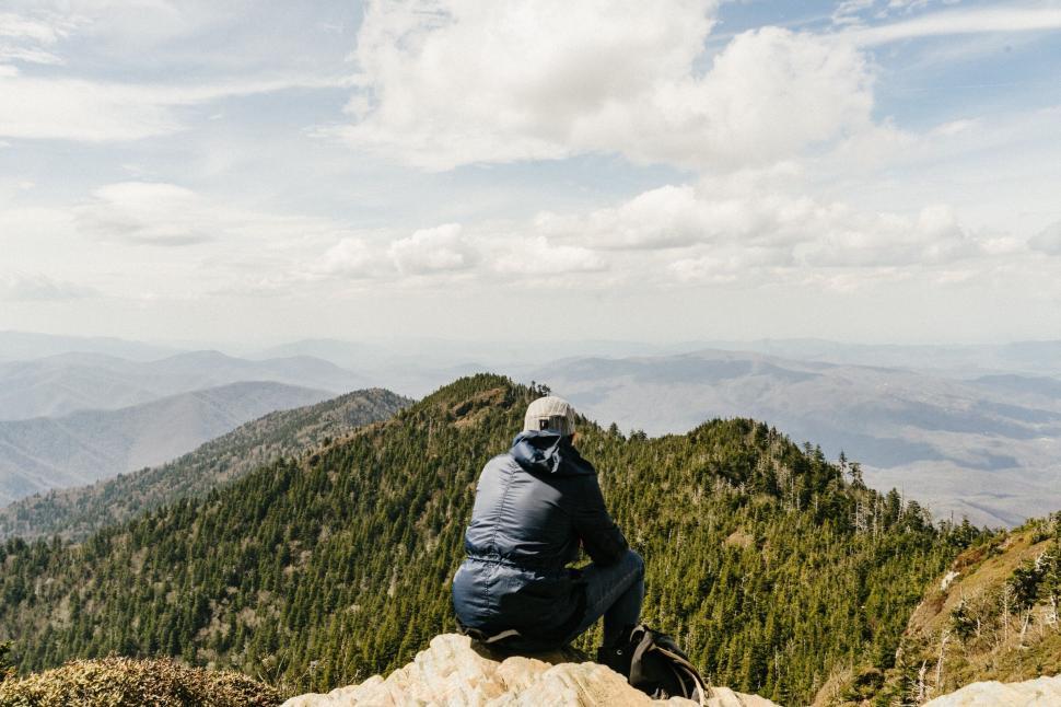 Free Image of Person sitting on mountain peak with view of vast mountain ranges 