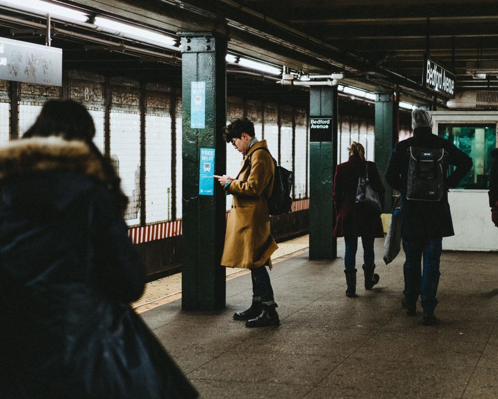 Free Image of People waiting at a subway station platform with green pillars. 