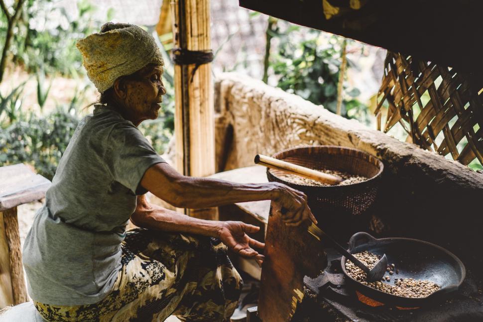 Free Image of Woman preparing food using traditional methods in outdoor setting 